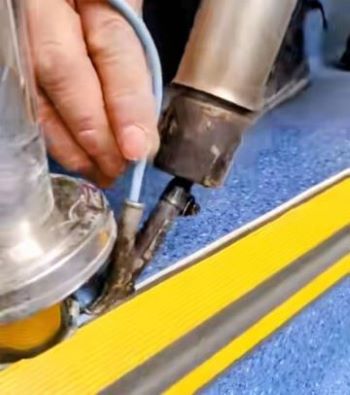 Técnico utilizando una soldadora térmica para sellar juntas o soldar vinilo en pisos sanitarios